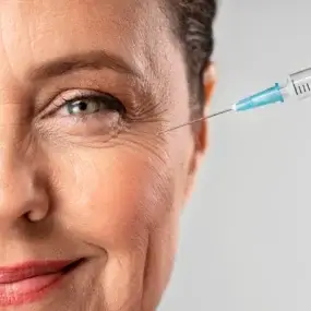 Visage d'une femme recevant un soin anti-âge sous la forme d'une injection de produit à côté de l'oeil
