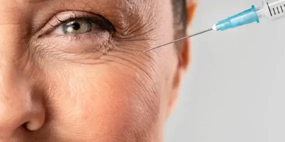 Visage d'une femme recevant un soin anti-âge sous la forme d'une injection de produit à côté de l'oeil